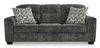 A three-seat sofa is presented in a gray-charcoal fabric with a textured, slightly mottled appearance.  The upholstery has a subtle pattern giving a variation in the shade throughout.  Three matching accent pillows, featuring a pattern of vertical stripes and light beige/cream tones against a darker gray background, are placed on the seat cushions. The sofa has gently curved armrests and dark-colored, faux-wood finish legs. The sofa is presented against a plain white background, which helps to highlight the sofa's color and texture.