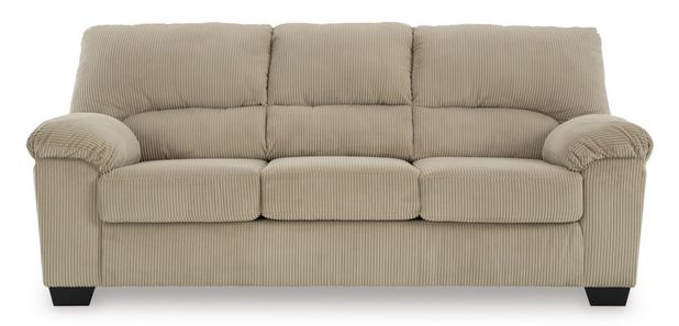 Full shot of a light beige or cream-colored three-seater sofa. The sofa has a corduroy-like textured fabric, with subtle vertical ribbed lines. The upholstery is a consistent tone. The sofa's arms are slightly flared and rounded, with a slightly tufted or quilted effect on the back and seat cushions. It has a classic, simple design with no embellishments. The sofa's legs are a dark, slightly brownish black color and are of a contemporary, slightly tapered design. The sofa is presented against a pure white background, which allows the color and details of the sofa to stand out clearly.