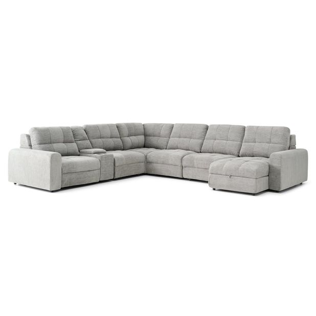 A light gray, sectional sofa is centered against a plain white background.    The sofa is an L-shape with a chaise lounge section extending from the main seating area. The upholstery appears to be a textured fabric with a subtle quilted pattern.  Each end of the sofa has padded armrests. A small, recessed storage space is visible in a section of the sofa.    The sofa is presented in a way that showcases its shape and style, and the soft light gray color makes it stand out.